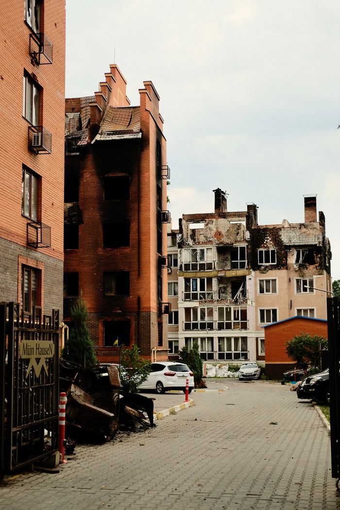 A street view of fire-damaged residential buildings in an urban area, showing destruction.
